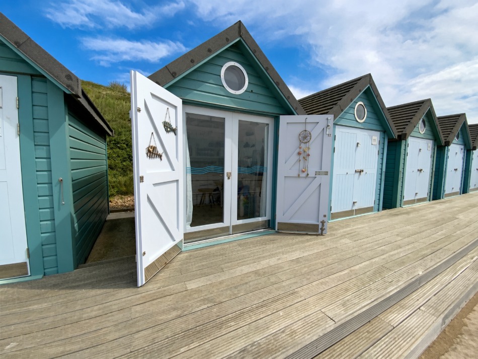 Hut Eleven's teal beach hut with its stable doors open onto the boardwalk, Southbourne beach.